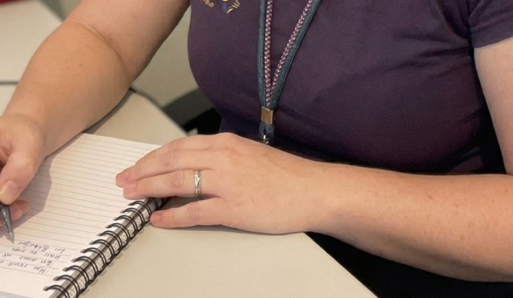 Mãos de mulher segurando um caderno de anotações com lista de ideias sobre o que postar no Instagram, simbolizando planejamento de conteúdo.